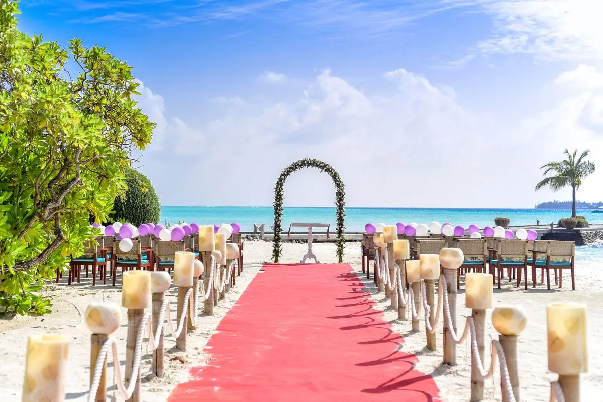 Beach wedding aisle with a red runner and rope posts